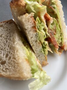 サワードウのセミヴィーガンサンドイッチの断面アボカドキムチレタスヴィーガンマヨの層が美しい