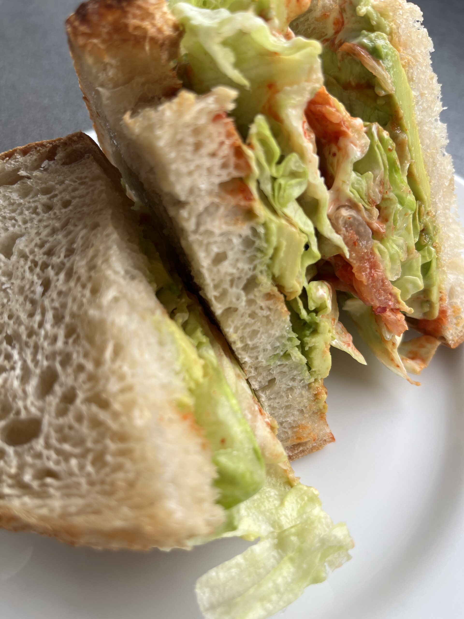 サワードウのセミヴィーガンサンドイッチの断面アボカドキムチレタスヴィーガンマヨの層が美しい